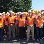 Group of people at a site tour wearing hard hats and reflective vests