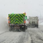 Back view of a plow with reflective markings and lights on a snowy road